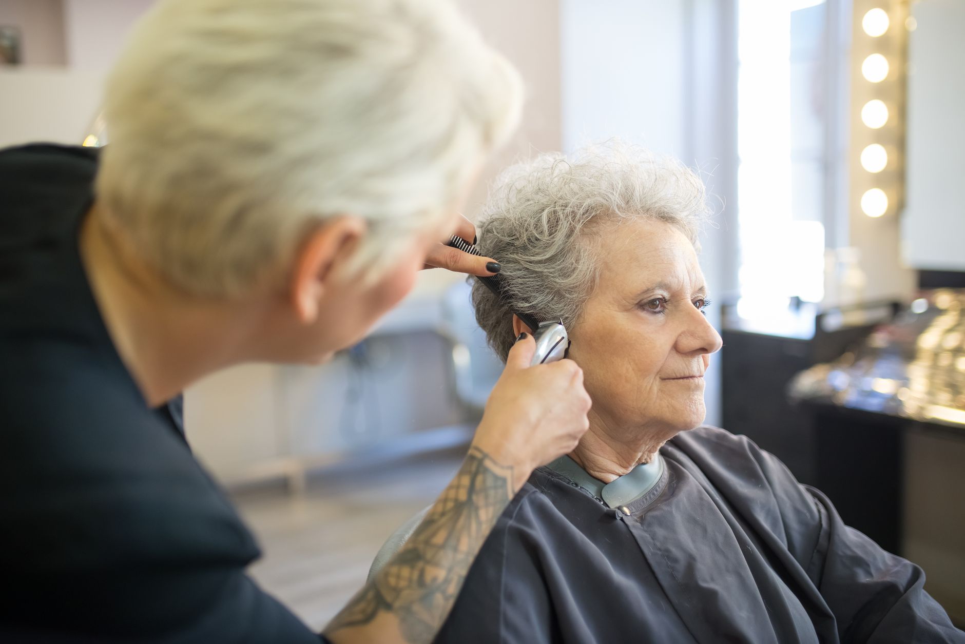Uma mulher idosa recebendo um corte de cabelo de um hairstylist habilidoso em um salão contemporâneo.
