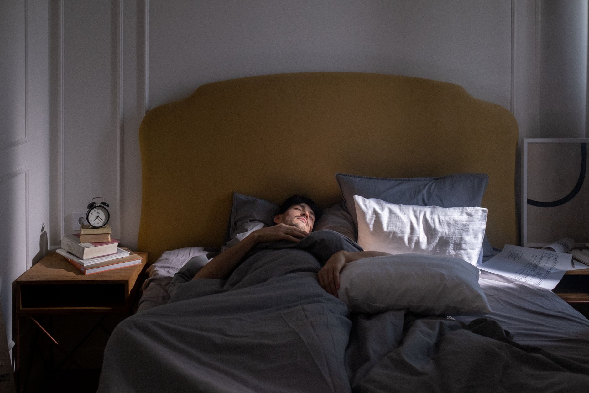 Um homem dormindo em uma cama aconchegante com a suave luz da manhã filtrando.