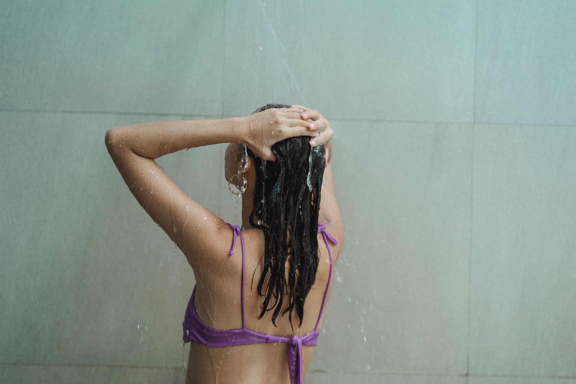 Mulher desfrutando de um chuveiro refrescante em ambientes internos, focando na higiene e relaxamento.