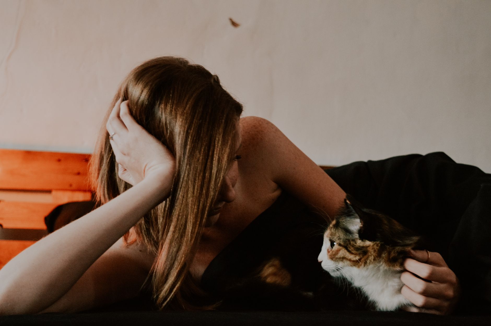 Um momento sereno de uma mulher e seu gato deitados na cama, capturado em ambientes internos.