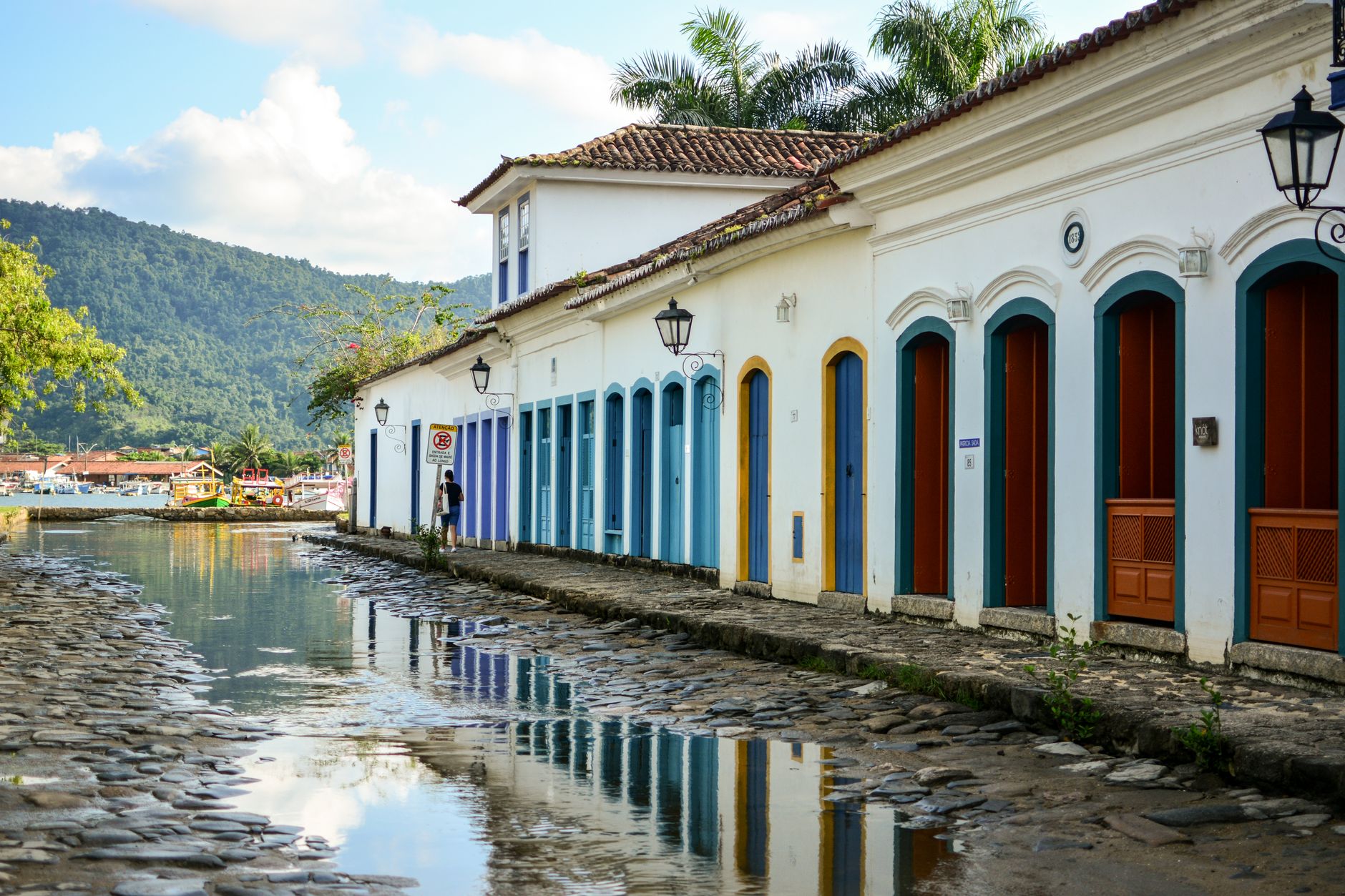 Edifícios históricos coloridos refletidos em uma rua de paralelepípedos em Paraty, Brasil.
