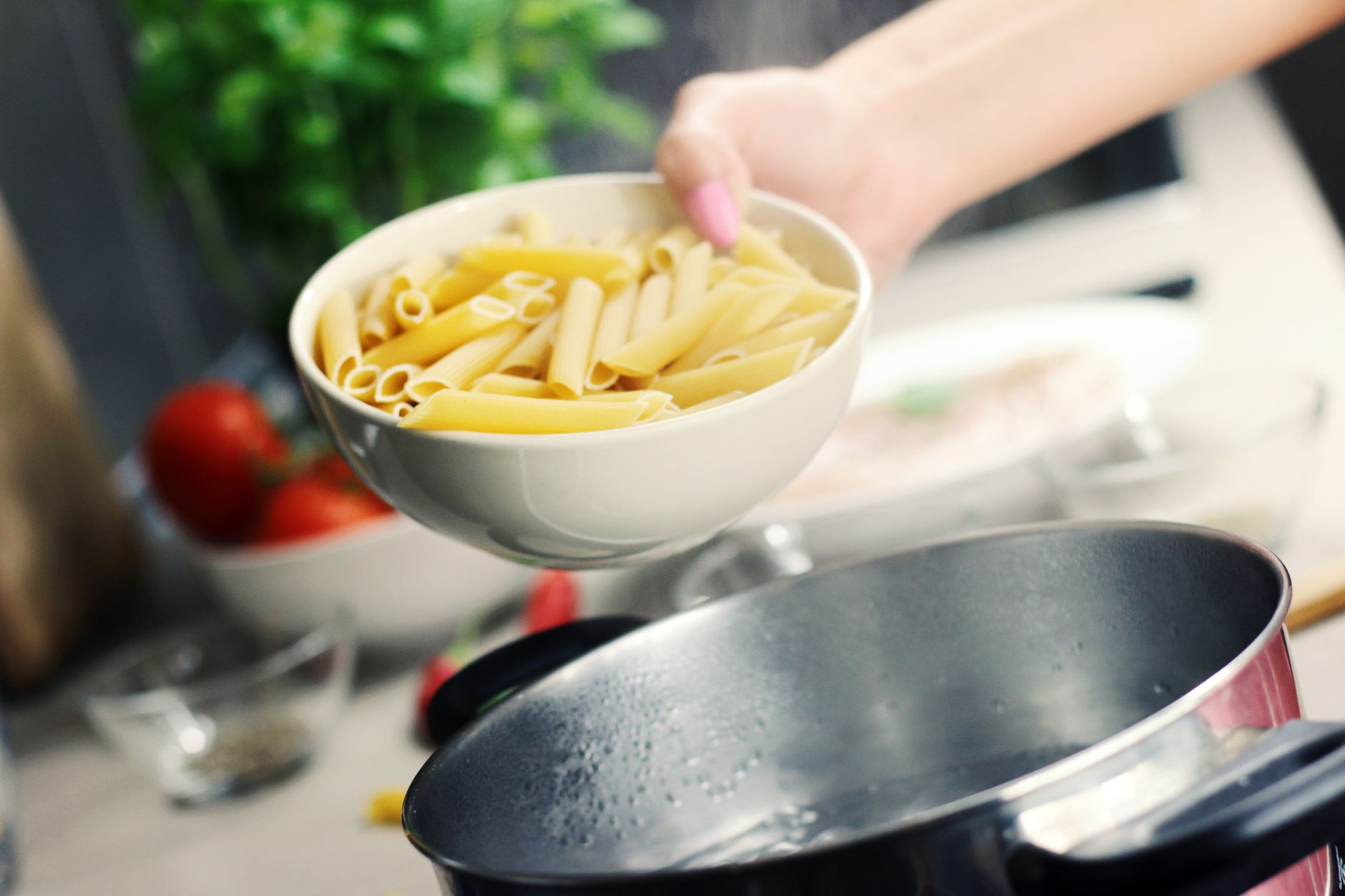 Uma tigela fresca de penne pronta para ser cozida em uma panela de aço inoxidável.