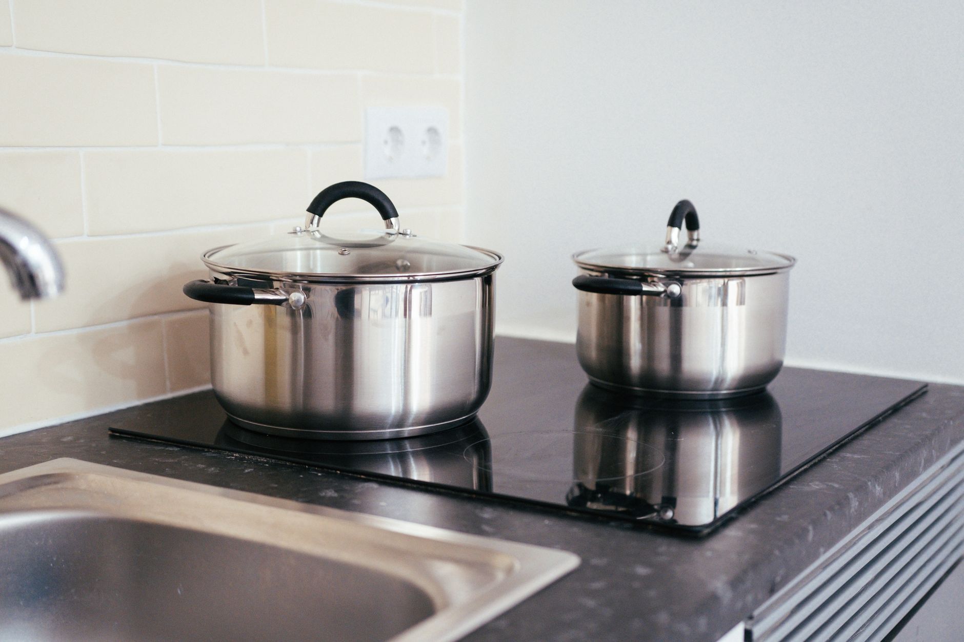 Cozinha contemporânea com panelas de aço inox em um fogão de indução.